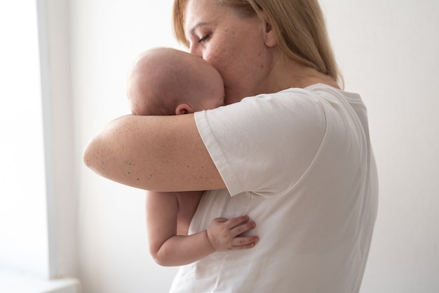 Jolie mère heureuse tenir baiser petit bébé garçon. Nouvelle vie. Famille heureuse. bébé rock. À la maison. Amour. Doux. Tendresse. photo de haute qualité