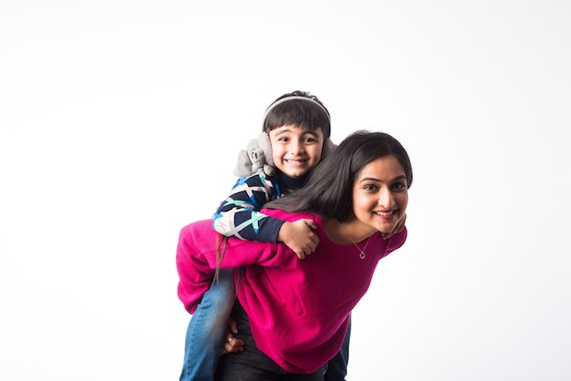 La jolie mère indienne avec son fils porte des vêtements d'hiver ou un pull sur fond blanc