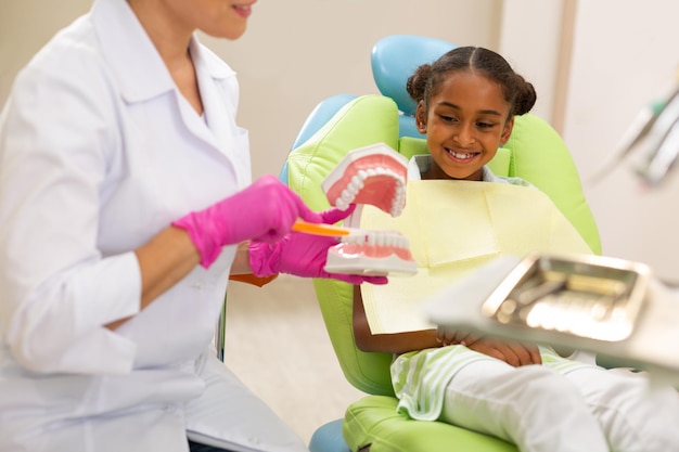 Photo jolie patiente assise sur une chaise de dentiste