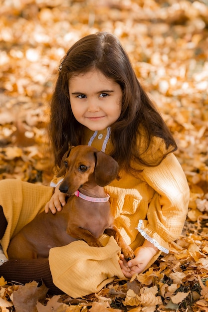 Photo une jolie petite brune se promène à l'automne avec un dachshund dans le parc.