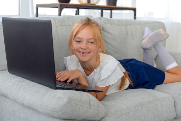 jolie petite étudiante faisant ses devoirs à la maison en ligne