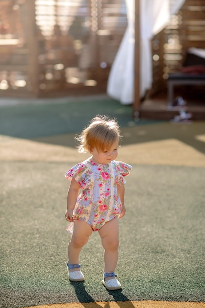 Jolie petite fille de 1 an sur la plage du complexe en été dans une tenue tendance