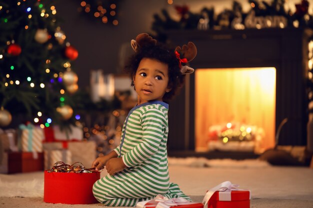 Jolie petite fille afro-américaine avec un cadeau à la maison la veille de Noël