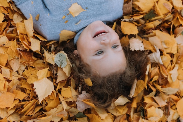 jolie petite fille allongée sur des feuilles jaunes dans le parc à l'automne bannière de carte d'automne en bonne santé