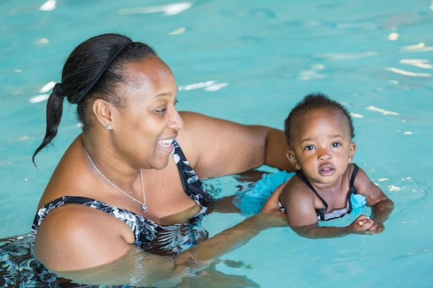 Jolie petite fille apprenant à nager dans la piscine intérieure.