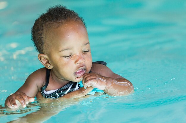 Jolie petite fille apprenant à nager dans la piscine intérieure.