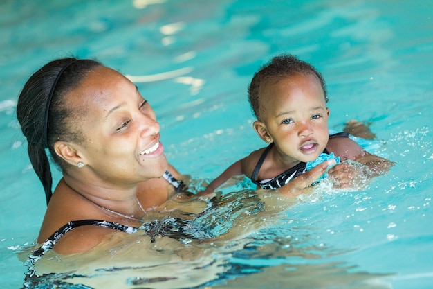 Jolie petite fille apprenant à nager dans la piscine intérieure.