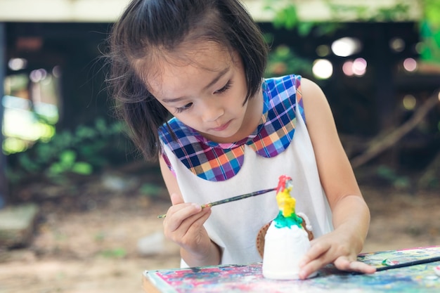 Photo jolie petite fille apprend joyeusement en dehors de la salle de classe avec une nature magnifique et un sourire éclatant