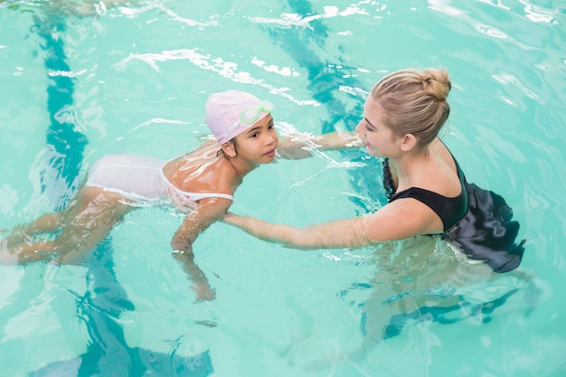 Jolie petite fille apprend à nager avec l&#39;entraîneur au centre de loisirs