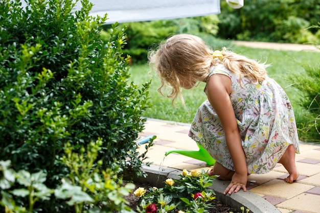 Jolie petite fille arrosant des plantes dans le jardin.