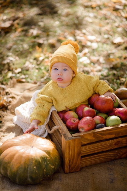 Jolie petite fille assise sur la citrouille et jouant dans la forêt d'automne