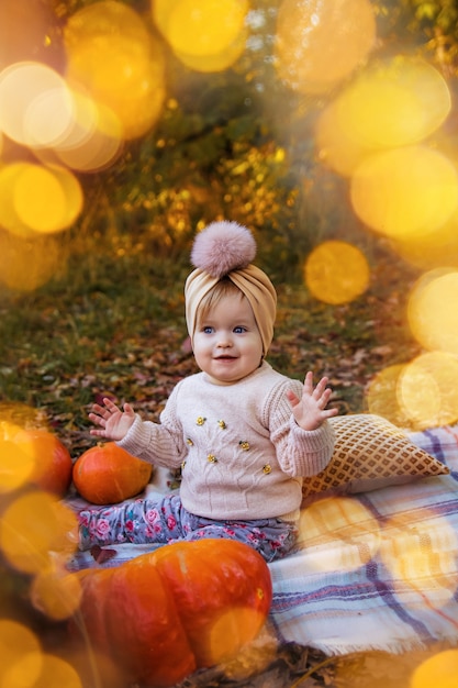 jolie petite fille assise dans un parc d'automne avec des lumières