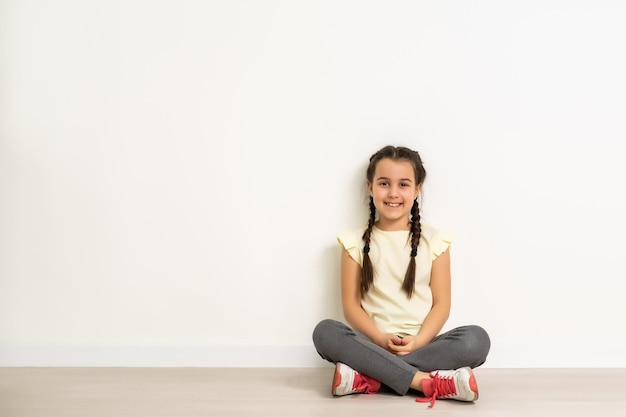 jolie petite fille assise sur le sol, isolée sur fond blanc.