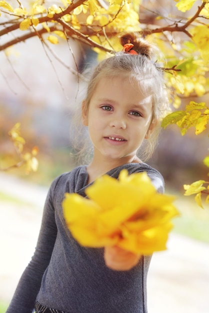 Jolie petite fille en automne avec des feuilles