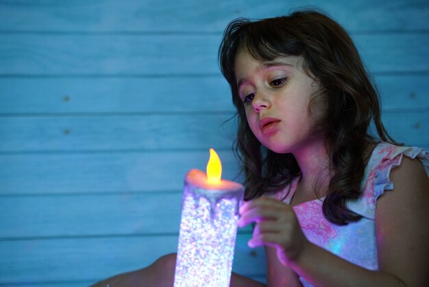 Jolie petite fille aux grands yeux regarde une bougie électrique