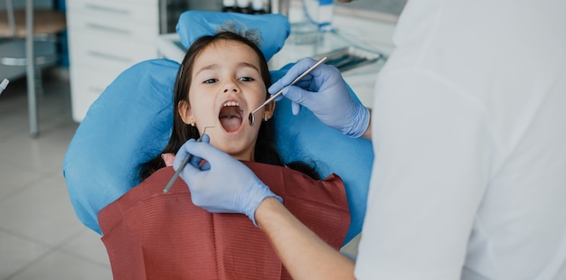Jolie petite fille ayant une chirurgie des dents par un stomatologue pédiatrique.