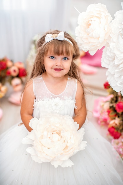 Jolie petite fille en belle robe avec des cheveux ondulés et un bouquet