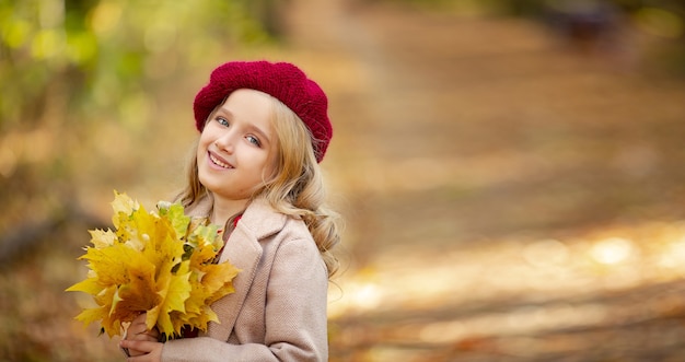 Jolie petite fille avec un béret rouge dans la forêt d'automne