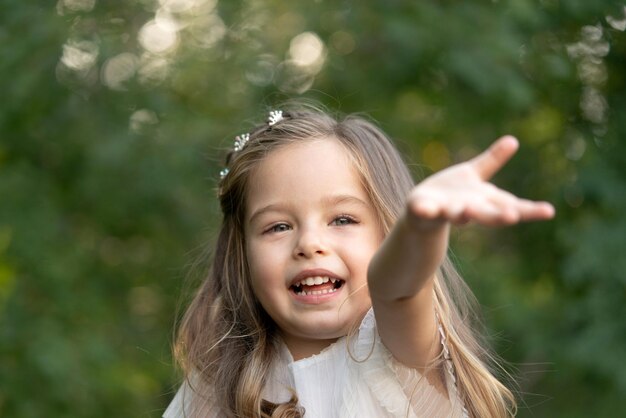 Une jolie petite fille a besoin d'aide et tire le bras de la main vers la caméra.