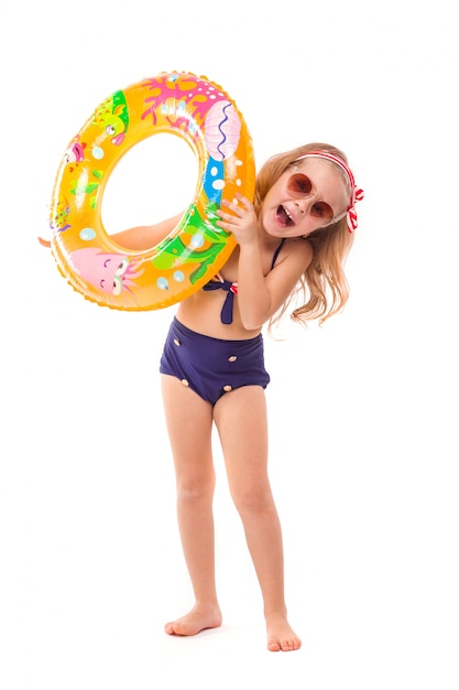 Jolie petite fille en bikini à rayures rouges, bas bleu, lunettes de soleil et couronne rose