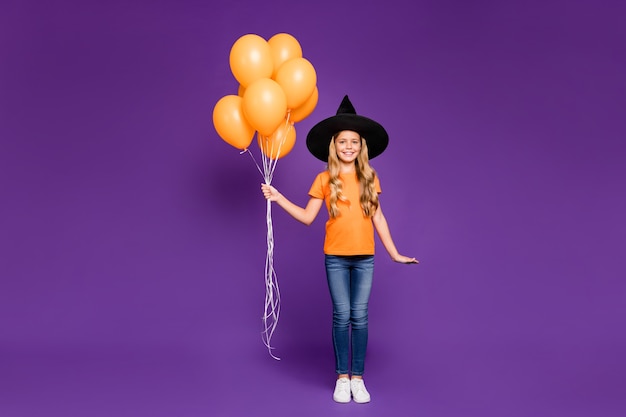 Jolie petite fille blonde avec un chapeau de sorcière et des ballons