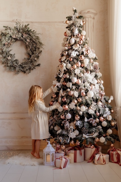 Jolie petite fille blonde en robe près de l'arbre de Noël