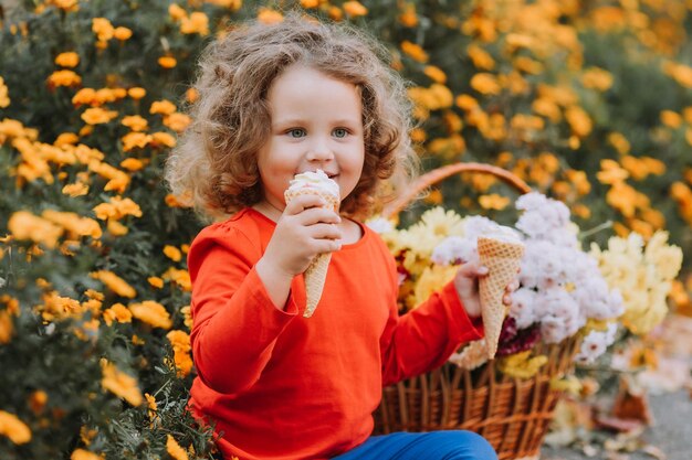 jolie petite fille bouclée mangeant des glaces dans le parc l'heure d'automne carte d'automne bannière de fleurs