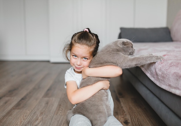 Jolie petite fille avec chat. Notion d'amoureux des animaux. Chat gris Scottish fold