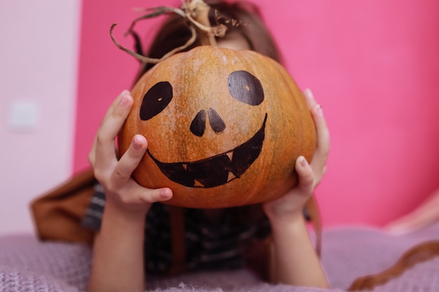 Jolie petite fille avec citrouille sculptée dans sa chambre