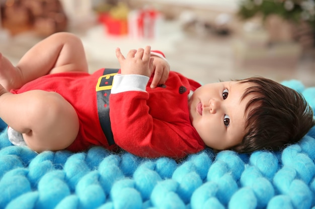 Jolie petite fille en costume de père Noël allongée sur un plaid à la maison