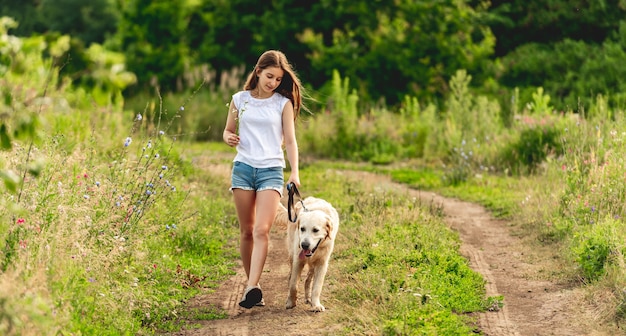 Jolie petite fille en cours d'exécution avec un chien adorable sur la route au sol en été