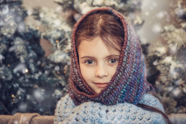 Jolie petite fille couverte d'un foulard chaud en attendant Noël