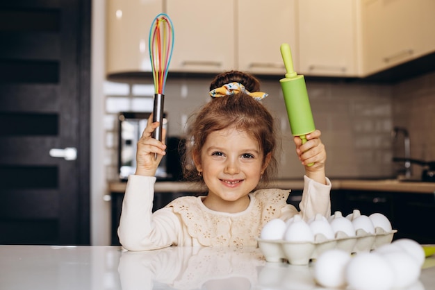 Jolie petite fille à la cuisine avec un rouleau à pâtisserie