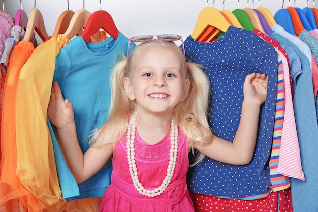 Jolie petite fille dans une armoire avec des vêtements