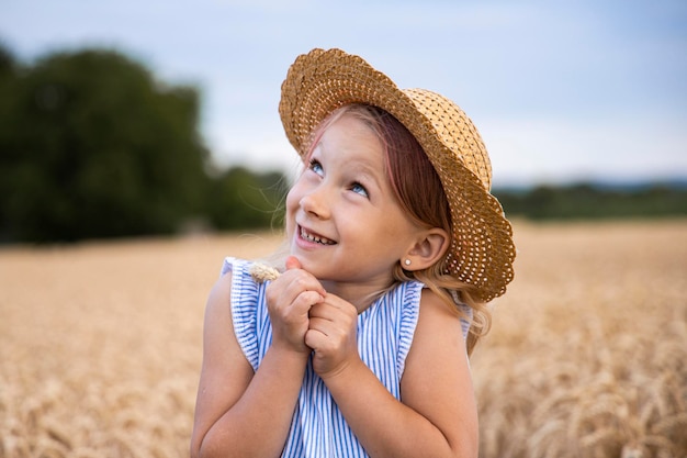 Une jolie petite fille dans un chapeau sur le fond d'un champ de blé