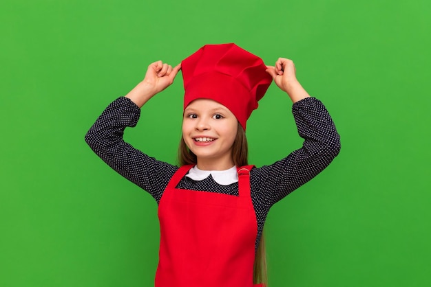 Une jolie petite fille dans un costume de cuisinier sur un fond vert isolé