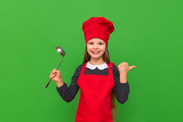 Une jolie petite fille dans un costume de cuisinier sur un fond vert isolé
