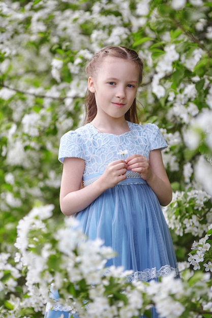 Jolie petite fille dans le jardin fleuri de pommier