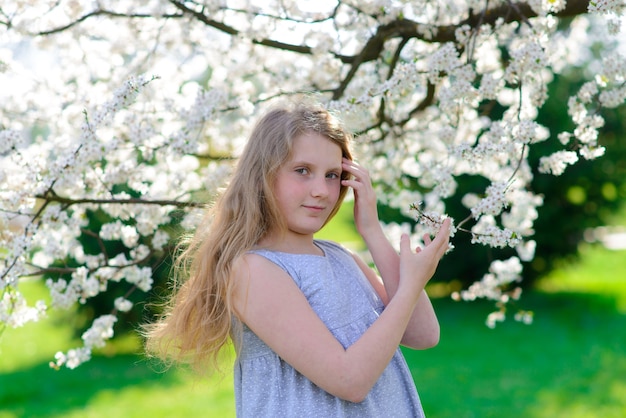 Jolie petite fille dans le jardin de pommiers en fleurs sur une belle journée de printemps