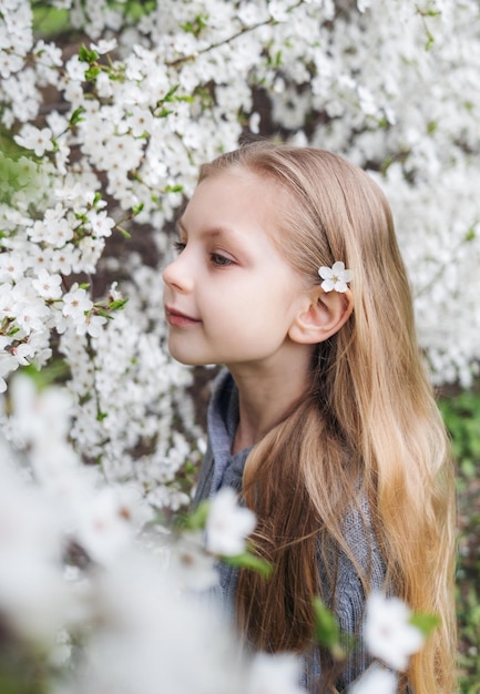 Jolie petite fille dans un jardin de printemps en fleurs