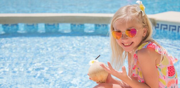 Jolie petite fille dans la piscine, boire du jus