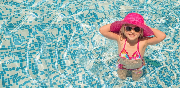Jolie petite fille dans la piscine, vacances d'été.