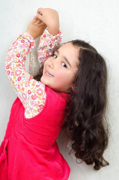 Jolie petite fille debout près du mur