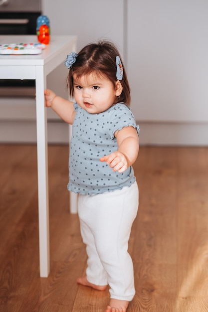 Jolie petite fille debout et se tenant à la table. Apprendre à marcher