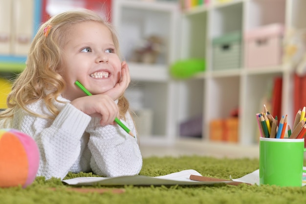 Jolie petite fille dessinant, allongée sur le sol