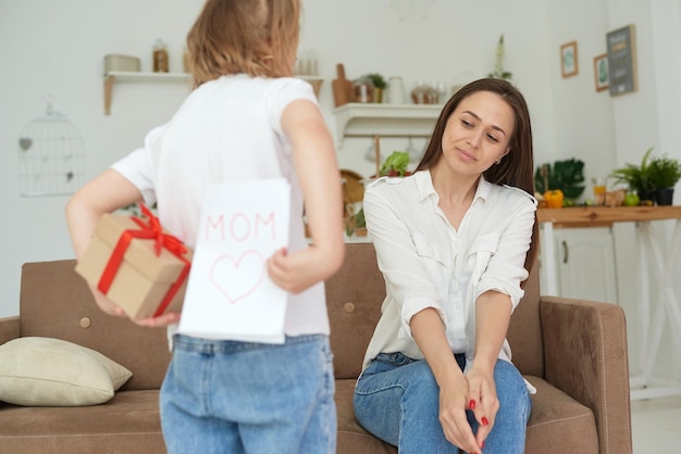 Une jolie petite fille donne à sa mère une carte et un cadeau pour le 8 mars ou la fête des mères Concept de famille aimante