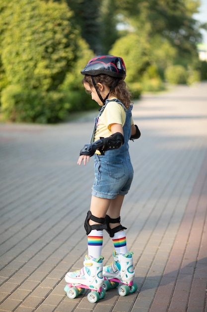 Jolie Petite Fille En équipement De Protection Et Rouleaux Se Dresse Sur  Une Passerelle Dans Le Parc Activité Estivale En Plein Air Pour Les Enfants