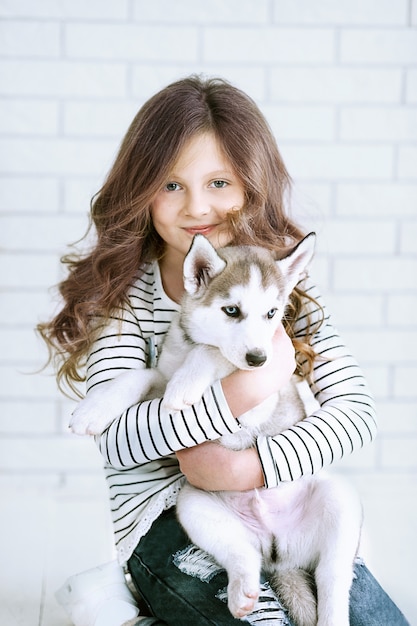 Jolie petite fille étreignant un chiot husky sur blanc