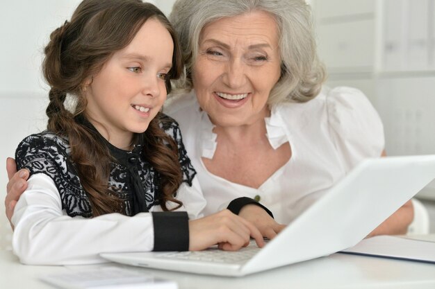 Jolie petite fille à faire ses devoirs avec mamie à l'aide d'un ordinateur