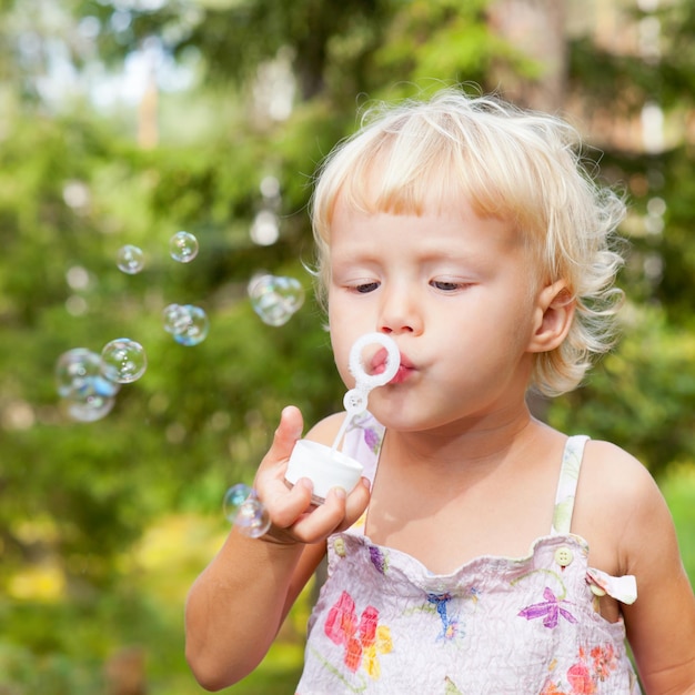 Jolie petite fille faisant des bulles de savon à l'extérieur